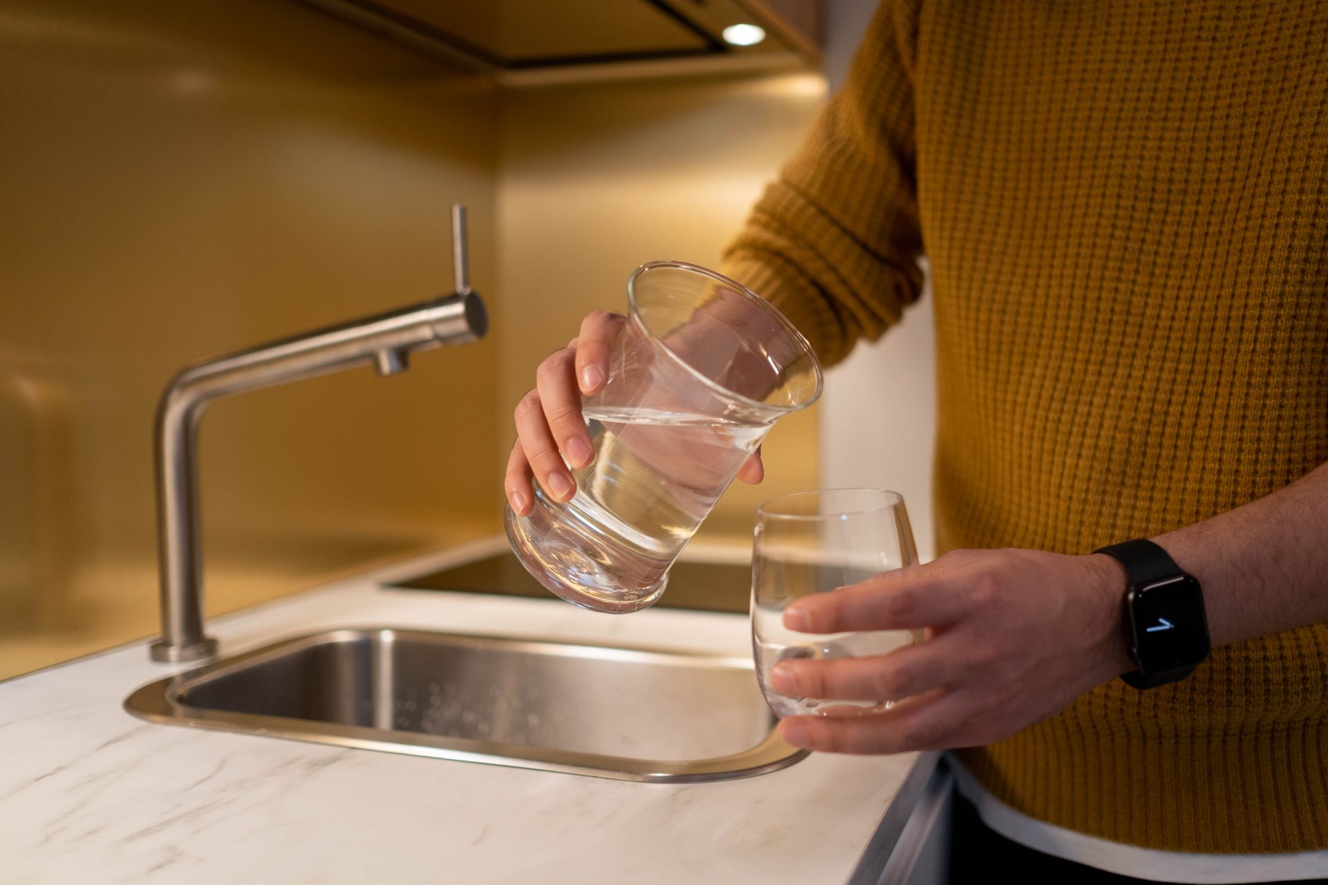 A plumber installing an under-sink water filter system in a kitchen.